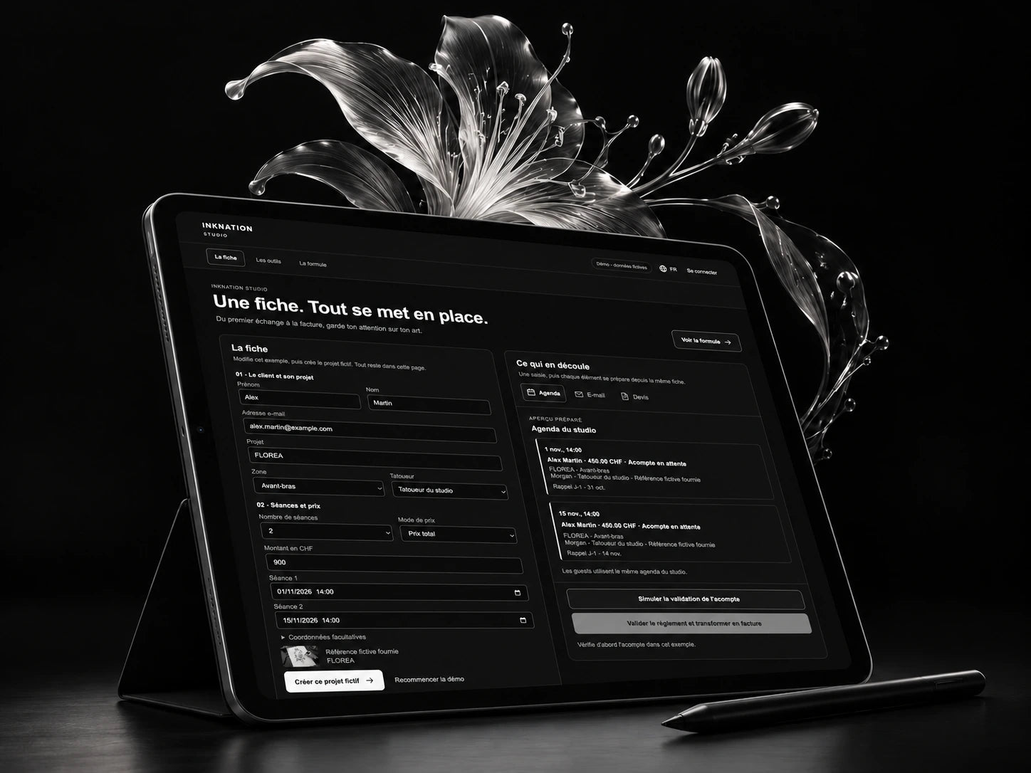 Mise en scène INKNATION Studio : tablette avec la fiche projet, stylet noir et création florale argentée.